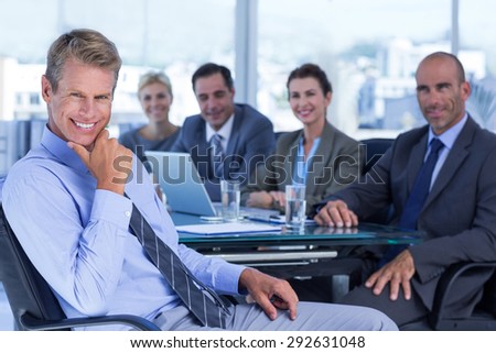 Businessman smiling at camera with colleagues behind in the office