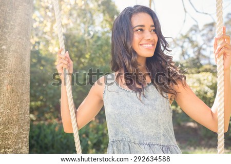 Pretty brunette swinging in park on a sunny day