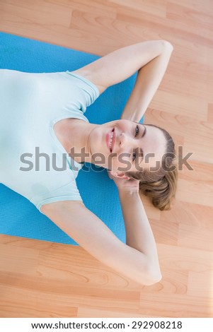 Smiling woman lying on exercise mat in fitness studio