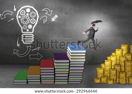 Businessman jumping holding an umbrella against steps made of books in front of light bulb drawing