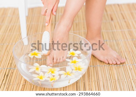 woman washing her feet in a bowl of flower at the spa institute