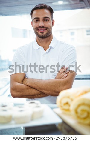 Smiling server in apron arm crossed at the bakery