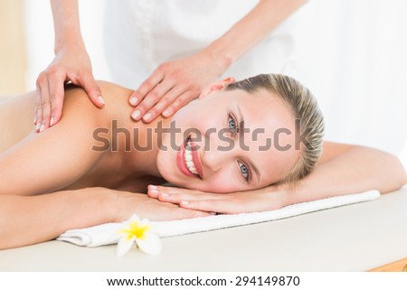 Pretty blonde enjoying a massage smiling at camera at the health spa