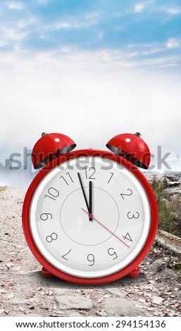Alarm clock counting down to twelve against stony path leading to misty cityscape