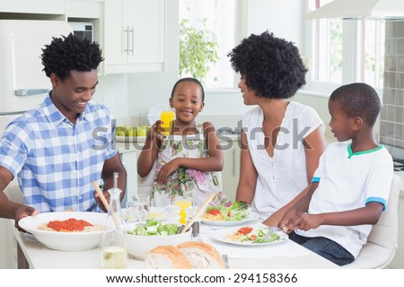 Happy family sitting down to dinner together at home in the kitchen