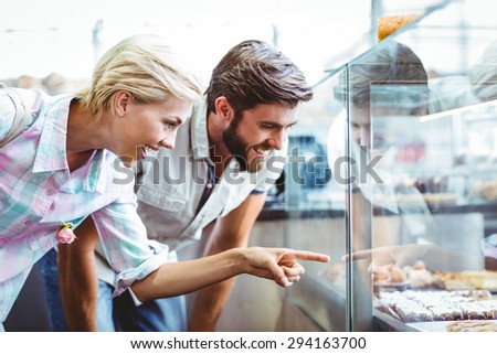 Cute couple on a date pointing cakes at the bakery