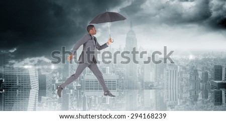 Businessman walking and holding umbrella against room with large window looking on city