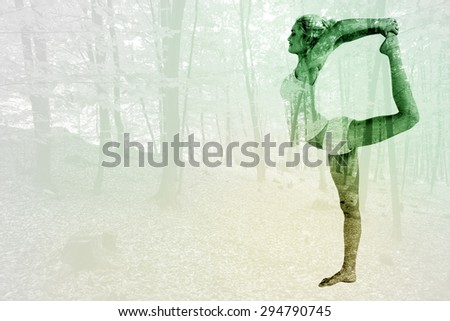 Sporty woman stretching body while balancing on one leg against trees in the autumnal forest
