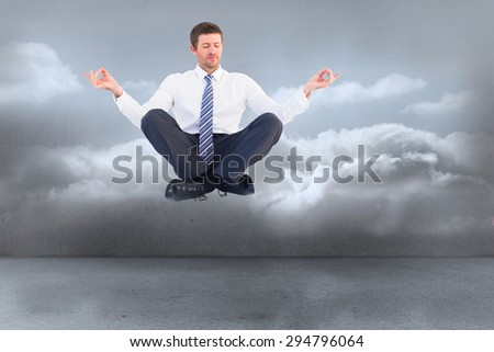 Businessman meditating in lotus pose against clouds in a room
