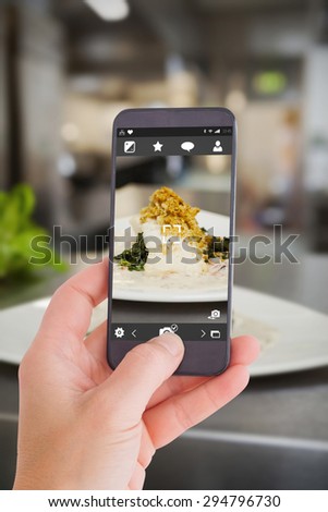 Female hand holding a smartphone against plate of food ready to go