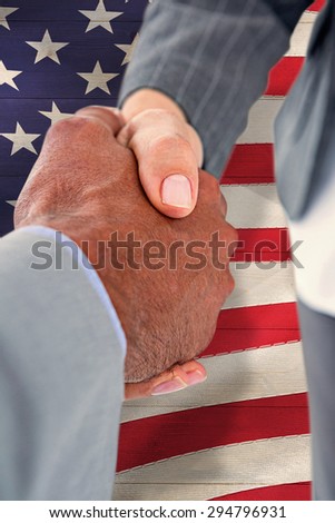 Businessman shaking hands with a co worker against pale grey wooden planks