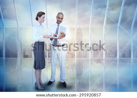 Business people using laptop against room with large window looking on city