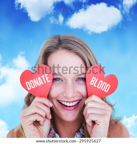 Woman holding heart cards against bright blue sky