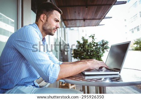 Attentive businessman using his laptop outside a cafe