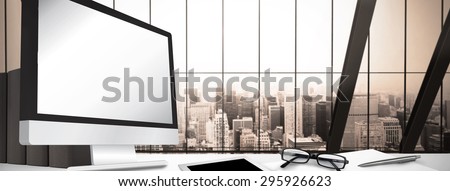 Computer screen against room with large window looking on city
