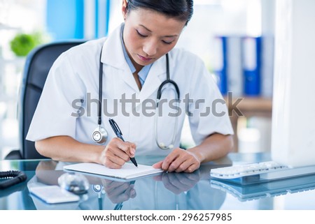 Concentrated doctor writing on notebook in medical office
