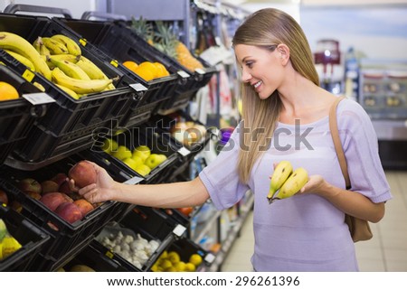 Smiling pretty blonde woman buying bananas at supermarket