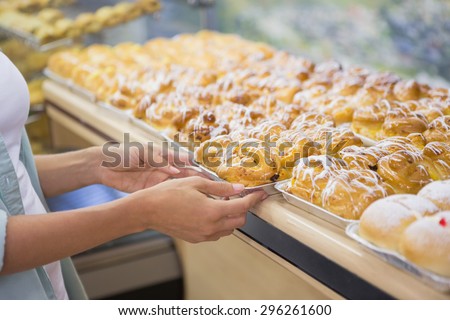 A baker presenting a new plates with pastries in a supermarket