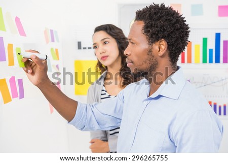 Young serious business people writing something on a sticky note