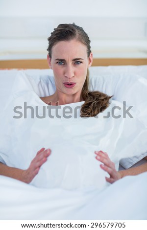 Portrait of pregnant woman suffering from labor pains lying in bed at hospital