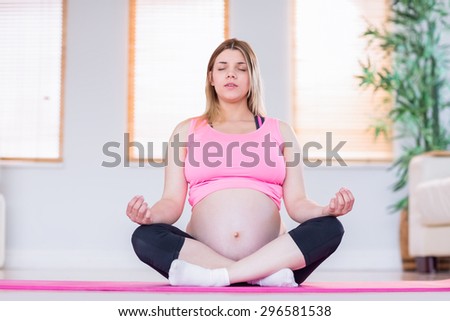 Pregnant woman doing yoga on exercise mat at home