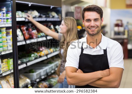 Portrait of a handsome seller with arm crossed at supermarket