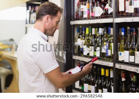 Handsome looking at wine bottle in supermarket