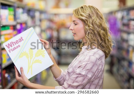 Side view of a pretty blonde woman reading a book in supermarket