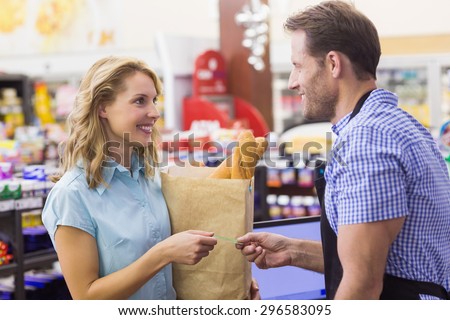 Smiling woman at cash register paying with credit card in supermarket