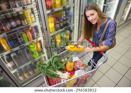 A pretty smiling blonde pointing at a bottle of oil at the supermarket