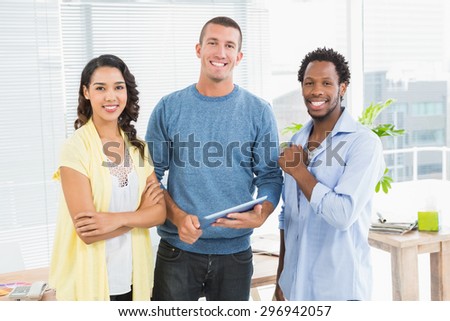 Portrait of smiling colleagues standing with tablet and looking at camera in the office