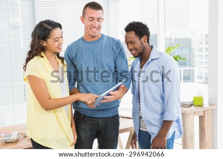 Portrait of smiling colleagues standing and using tablet computer in the office