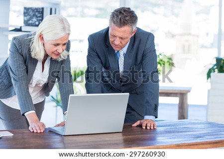 Serious business people looking at laptop in office