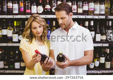 Casual couple looking at wine bottle in supermarket