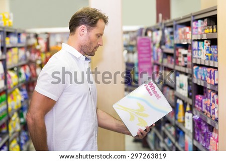 Side view of handsome looking at a box in supermarket