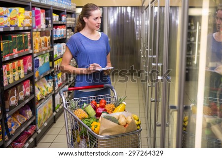 Pretty woman looking at product on freezer at supermarket