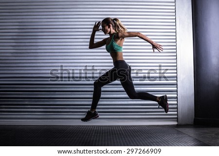 Side view of a muscular woman running in exercise room