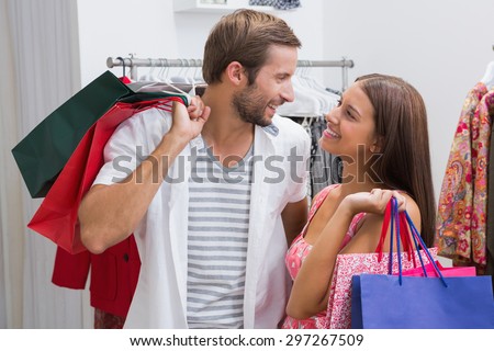 Smiling couple with shopping bags looking at each other at a boutique