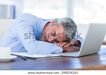 Businessman sleeping on laptop computer in office