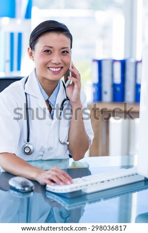 Smiling doctor looking at camera and having phone call in medical office