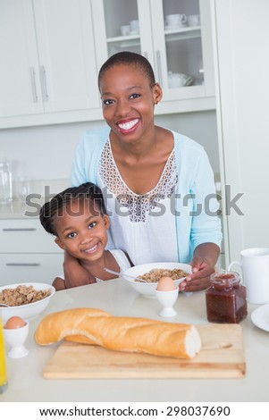 Portrait smiling mother and daughter eating together at home in the kitchen