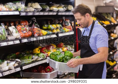 Smiling handsome worker holding a box with vegetable in supermarket