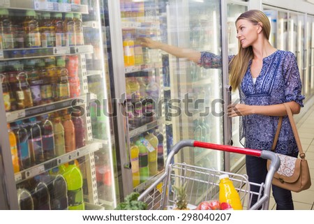 a woman taking a bottle in the frozen aisle at supermarket