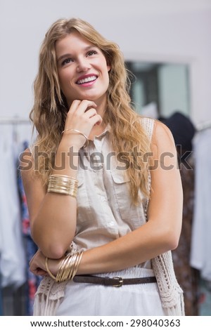 A pretty smiling blonde woman looking away in a clothing store