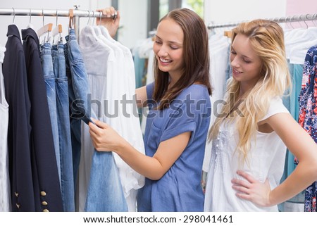 Enthusiastic friends browsing in the clothes rack
