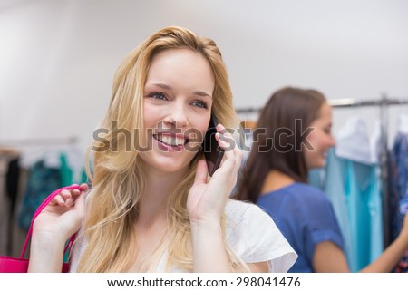 Pretty blonde talking on the phone in the clothing store