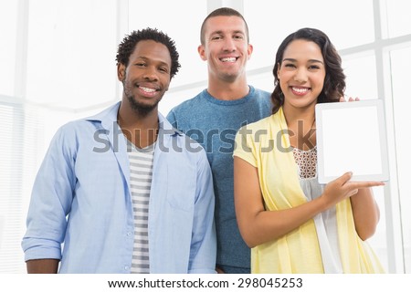 portrait of smiling colleagues presenting tablet computer and looking at camera in the office