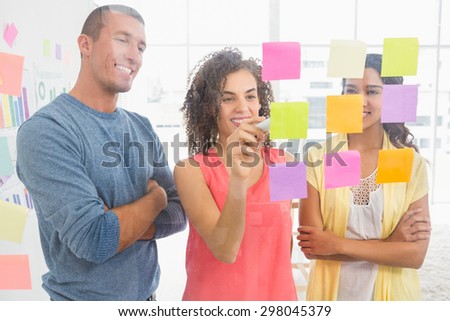 Smiling coworkers writing on sticky notes in the office