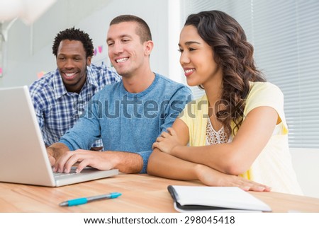Smiling colleagues working together with laptop in the office