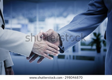 Close up of business people shaking their hands against office